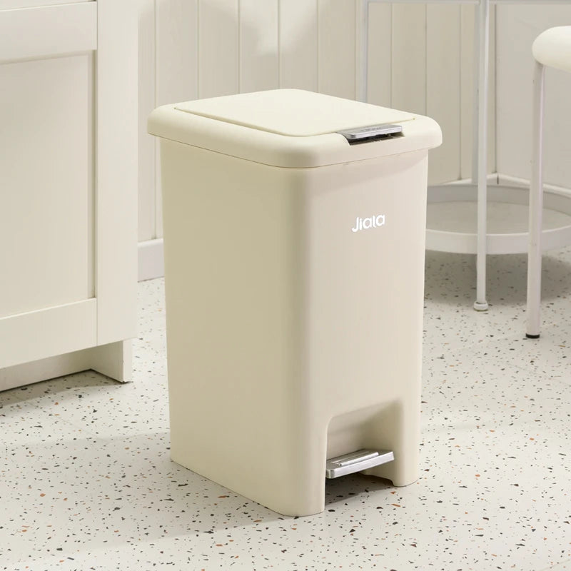 Poubelle de cuisine à pédale beige en face d'un meuble