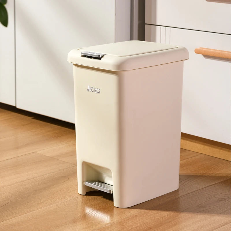 Poubelle de cuisine à pédale beige devant un meuble blanc