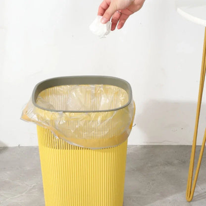 Une personne jette un papier dans une poubelle nordique jaune